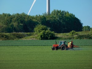 A tractor is spraying a field in the spring. Un tracteur asperge un champ durant le printemps.